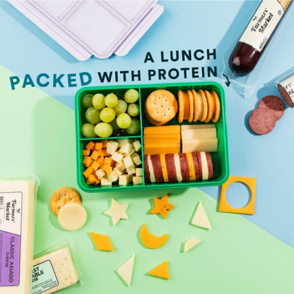 A lunch box with crackers, cheese and fruit.