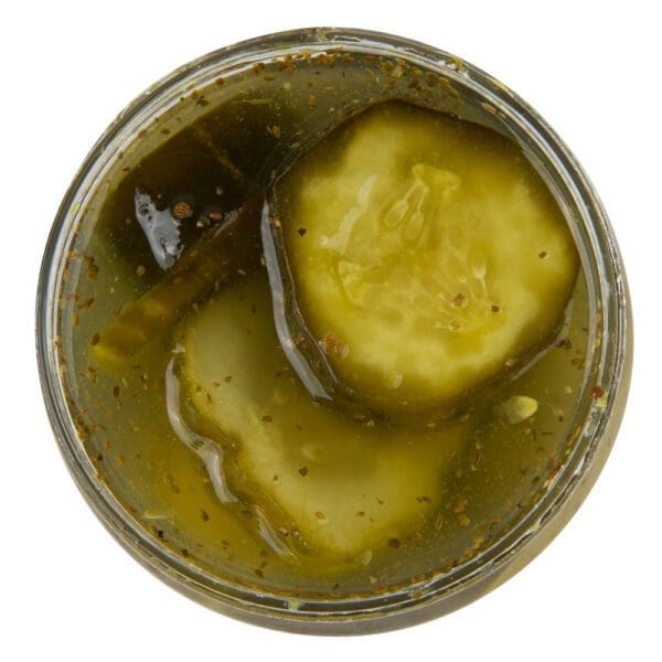 A cup of pickles sitting on top of the table.