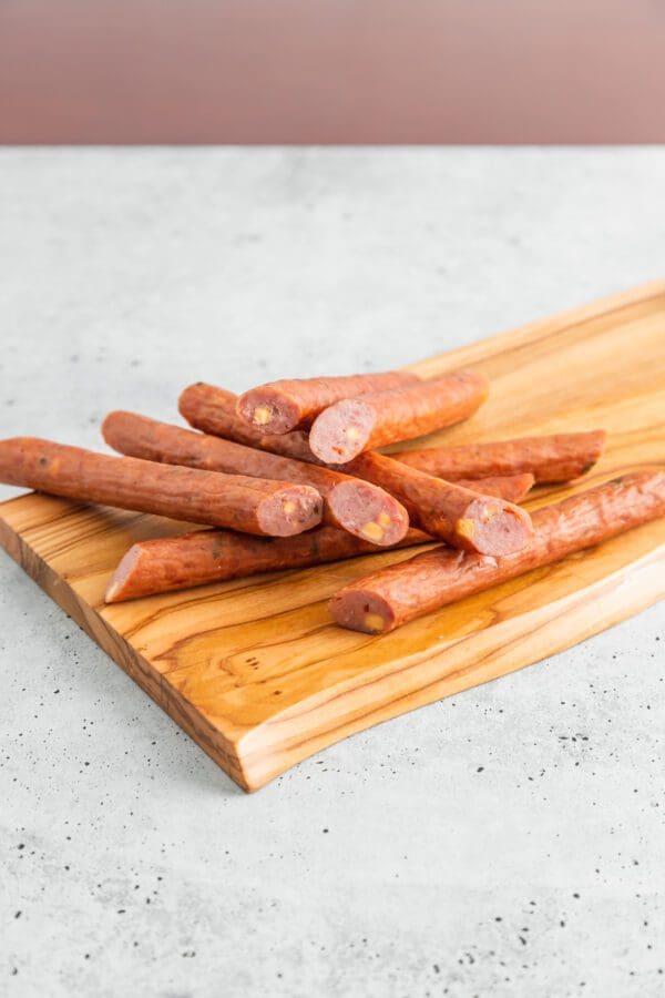 Greenridge All-Natural Grass Fed Beef sticks are on a wooden cutting board.
